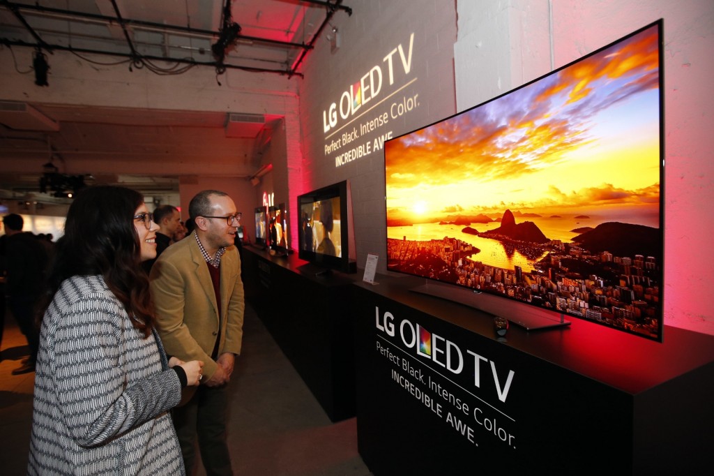 Attendees marvel at an LG Curved 4K UHD OLED TV (Model 65EG9600) at LG and Netflix’s Dare to See OLED event in New York. (Photo by Jason DeCrow/Invision for LG Electronics/AP Images)