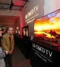 Attendees marvel at an LG Curved 4K UHD OLED TV (Model 65EG9600) at LG and Netflix’s Dare to See OLED event in New York. (Photo by Jason DeCrow/Invision for LG Electronics/AP Images)