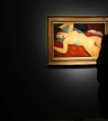 A member of staff at Christie's auction house looks at a painting by Italian artist Amedeo Modigliani entitled 'Ne Couche' 1917-1918 as it goes on show in London, Friday, Oct. 9, 2015. The painting will be sold in New York in Nov. 9, with its estimate in the region of 100 million US dollars, (65 million pounds sterling). (AP Photo/Alastair Grant)