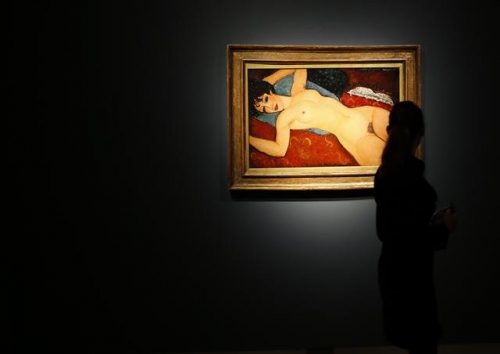 A member of staff at Christie's auction house looks at a painting by Italian artist Amedeo Modigliani entitled 'Ne Couche' 1917-1918 as it goes on show in London, Friday, Oct. 9, 2015. The painting will be sold in New York in Nov. 9, with its estimate in the region of 100 million US dollars, (65 million pounds sterling). (AP Photo/Alastair Grant)