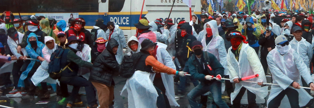 Protesters wearing masks pull ropes to topple a police bus during a rally in Gwanghwamun, central Seoul, on Nov. 14. The ruling Saenuri Party is moving to ban activists from wearing masks to hide their identity. (Yonhap)