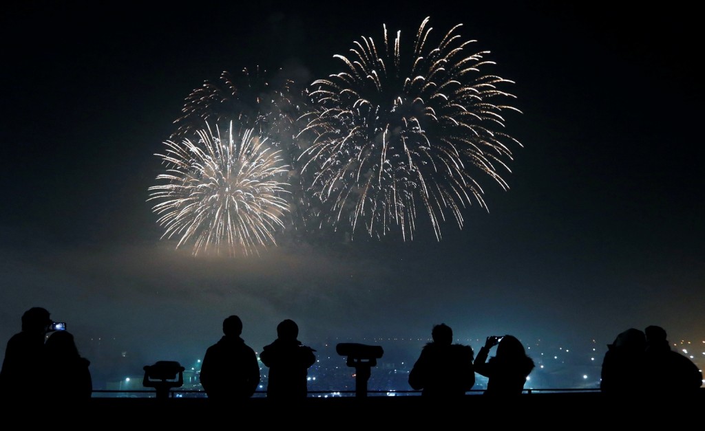 People watch and use their smartphones to take picture of fireworks, to celebrate the New Year at the Imjingak Pavilion near the border village of Panmunjom in Paju, South Korea, Friday, Jan. 1, 2016. (AP Photo/Lee Jin-man)