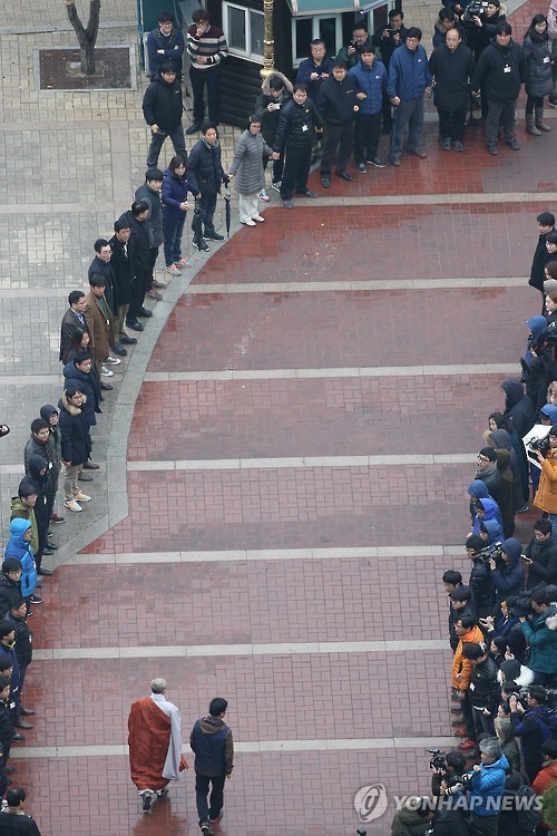 Han Sang-gyun, head of an umbrella union, and Ven. Dobeop walk together down a path at the Jogye Temple in Seoul on Dec. 10, 2015, as temple officials make way for them. Han, who has been taking shelter at the temple since Nov. 16, turned himself in to police who sought to arrest him on suspicion of organizing violent mass rallies. (Yonhap)