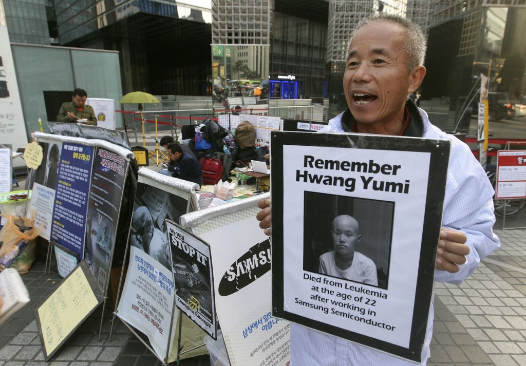 In this Oct. 23, 2015 photo, Hwang Sang-gi, a founding member of advocacy group Banolim, holds a picture of his daughter Yu-mi during an interview denouncing Samsung’s response in its latest negotiations with sick workers outside Samsung buildings in Seoul, South Korea. Yu-mi’s death from leukemia in 2007 galvanized concern about conditions at Samsung factories and South Korea’s semiconductor industry in general. Samsung’s hopes of ending years of acrimony and bad publicity over whether its semiconductor factories caused cancer have hit a hitch: some sickened workers and their families say they’ll never accept its highly conditional offer of financial assistance. (AP Photo/Ahn Young-joon)