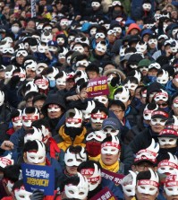 South Korean protesters attend an anti-government rally in downtown Seoul, South Korea, Saturday, Dec. 5, 2015. Wearing white half-masks and carrying flowers and banners, thousands of South Koreans marched in Seoul on Saturday against conservative President Park Geun-hye, who had compared masked protesters to terrorists after clashes with police broke out at a rally last month. (AP Photo/Ahn Young-joon)