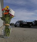 Flowers are left by the side of the road as a San Bernardino police officer blocks the road leading to the site of yesterday's mass shooting on Thursday, Dec. 3, 2015 in San Bernardino, Calif. A heavily armed man and woman dressed for battle opened fire on a holiday banquet for his co-workers Wednesday, killing multiple people and seriously wounding others in a precision assault, authorities said. Hours later, they died in a shootout with police. (AP Photo/Chris Carlson)