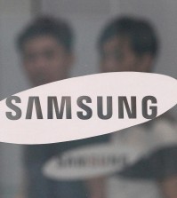 In this July 17, 2015 file photo, employees walk past a logo of Samsung Group at the head office of Samsung C&T Corp. in Seoul, South Korea. South Korea's financial regulator said Friday, Dec. 4, 2015 it has launched an investigation into possible insider trading by Samsung executives related to a contentious takeover deal. (AP Photo/Ahn Young-joon, File)