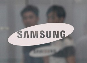 In this July 17, 2015 file photo, employees walk past a logo of Samsung Group at the head office of Samsung C&T Corp. in Seoul, South Korea. South Korea's financial regulator said Friday, Dec. 4, 2015 it has launched an investigation into possible insider trading by Samsung executives related to a contentious takeover deal. (AP Photo/Ahn Young-joon, File)