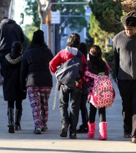 Parents take their children return home from school early Tuesday, Dec. 15, 2015, in Los Angeles. All schools in the vast Los Angeles Unified School District, the nation's second largest, have been ordered closed due to an electronic threat Tuesday. (AP Photo/Ringo H.W. Chiu)