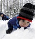 Leon Perkins, 3, leans forward to take a bite of snow as he plays with his brother Conner, left, 2, and his father Erin, Tuesday, Dec. 22, 2015, at Snoqualmie Pass, Wash. The Seattle family headed to the mountains Tuesday to enjoy the new snow that fell overnight. A weather pattern that could be associated with El Nino has turned winter upside-down across the U.S. during a week of heavy holiday travel, bringing spring-like warmth to the Northeast, a risk of tornadoes in the South and so much snow in parts of the West that there are concerns about avalanches. On Christmas Day, it could be warmer in New York City than Los Angeles.(AP Photo/Elaine Thompson)