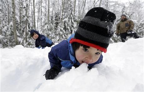 Leon Perkins, 3, leans forward to take a bite of snow as he plays with his brother Conner, left, 2, and his father Erin, Tuesday, Dec. 22, 2015, at Snoqualmie Pass, Wash. The Seattle family headed to the mountains Tuesday to enjoy the new snow that fell overnight. A weather pattern that could be associated with El Nino has turned winter upside-down across the U.S. during a week of heavy holiday travel, bringing spring-like warmth to the Northeast, a risk of tornadoes in the South and so much snow in parts of the West that there are concerns about avalanches. On Christmas Day, it could be warmer in New York City than Los Angeles.(AP Photo/Elaine Thompson)
