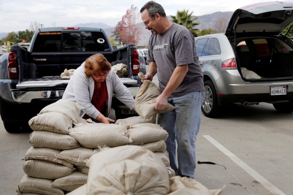 Residents Trina Gonzalez, left, and Todd Peterson stockpile sandbags to protect their homes from the rain in Glendora, Calif., Monday, Jan. 4, 2016. After all the talk, El Nino storms have finally lined up over the Pacific and started soaking drought-parched California with rain expected to last for most of the next two weeks, forecasters said Monday. (AP Photo/Nick Ut)