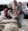 Residents Trina Gonzalez, left, and Todd Peterson stockpile sandbags to protect their homes from the rain in Glendora, Calif., Monday, Jan. 4, 2016. After all the talk, El Nino storms have finally lined up over the Pacific and started soaking drought-parched California with rain expected to last for most of the next two weeks, forecasters said Monday. (AP Photo/Nick Ut)