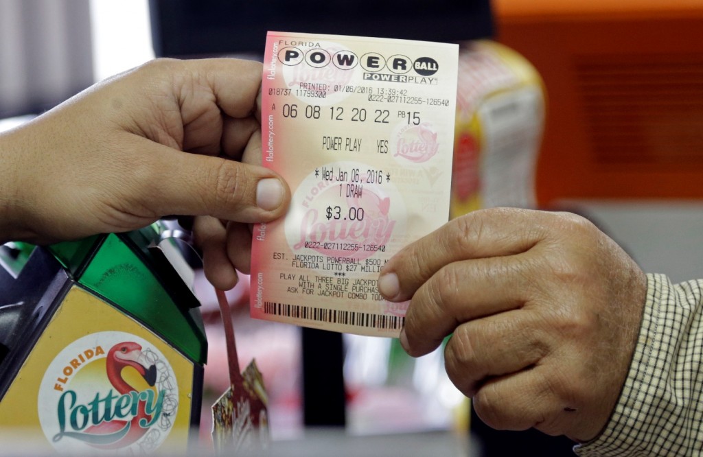 A clerk hands over a Powerball ticket to a customer, Wednesday, Jan. 6, 2016, at a local grocery store in Hialeah, Fla. The estimated Powerball jackpot for Wednesday night has soared to $500 million. The last time Powerball had grown this large was in February 2015, when three winners split a $564.1 million prize. (AP Photo/Alan Diaz)