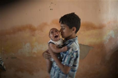 FILE - In this Dec. 23, 2015, file photo, 10-year-old Elison nurses his 2-month-old brother Jose Wesley, who was born with microcephaly, at their house in Poco Fundo, Pernambuco state, Brazil. The U.S. Centers for Disease Control and Prevention said Wednesday, Jan. 13, 2016, that it has found the strongest evidence so far of a possible link between a mosquito-borne virus and a surge of birth defects in Brazil. (AP Photo/Felipe Dana, File)