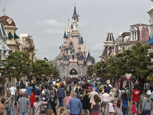 FILE - This Tuesday, May 12, 2015 file photo shows visitors walking toward the Sleeping Beauty's Castle, background, at Disneyland Paris in Marne la Vallee, east of Paris, France. A French police official says a man found to be carrying two handguns has been arrested at a hotel at Disneyland Paris. France remains under a state of emergency since Nov. 13 Islamic extremist attacks around Paris that killed 130 people. (AP Photo/Michel Euler, File)
