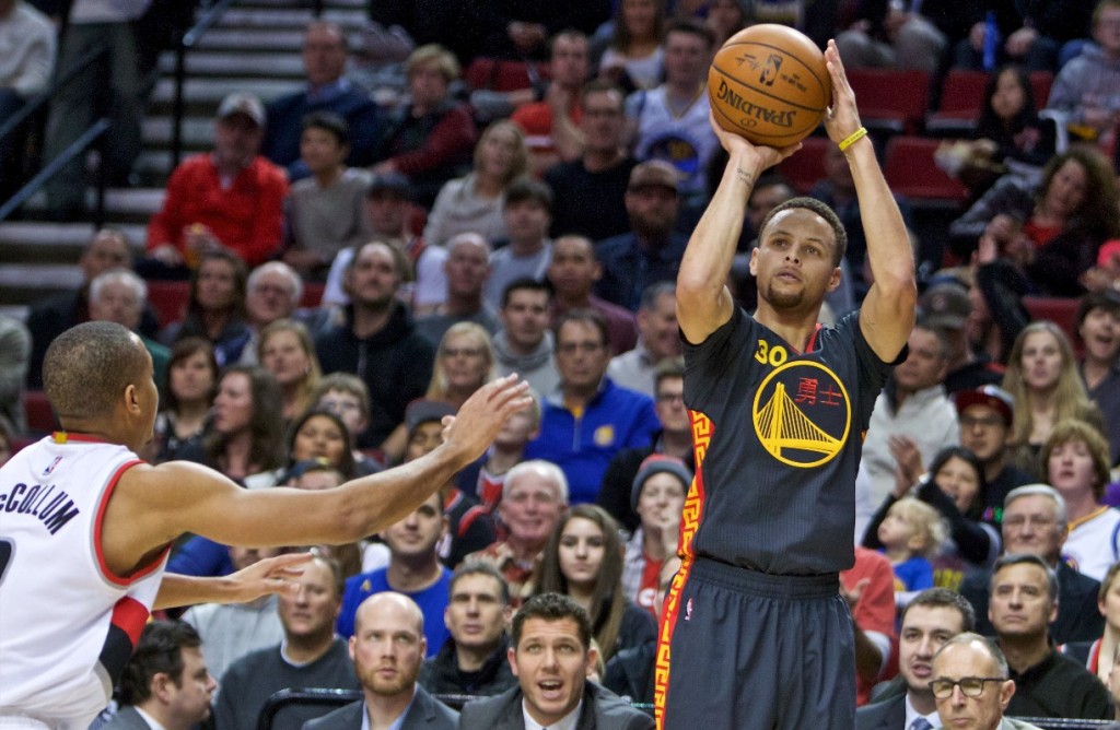 Golden State Warriors guard Stephen Curry, right, shoots over Portland Trail Blazers guard C.J. McCollum, left, during the first half of an NBA basketball game in Portland, Ore., Friday, Feb. 19, 2016. (AP Photo/Craig Mitchelldyer)