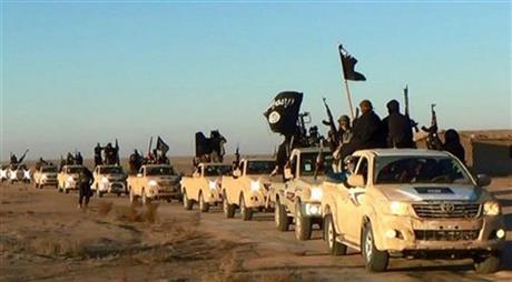FILE - In this undated file photo released online in the summer of 2014 on a militant social media account, which has been verified and is consistent with other AP reporting, militants of the Islamic State group hold up their weapons and wave its flags on their vehicles in a convoy on a road leading to Iraq, in Raqqa, Syria. The extremist group that once bragged about minting its own currency is now accepting only U.S. dollars in Raqqa, slashing salaries across the board and imposing “exit fees” for those trying to leave its domain. (Militant photo via AP, File)