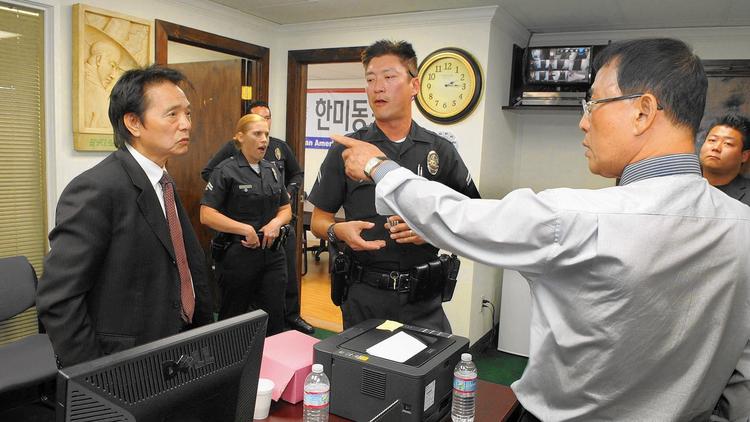 With police officers looking on, Sung Hoon Yoon, left, and Sung Woong Kim argue in the offices of the Korean American United Foundation in 2014. Yoon and Kim each claim to be the legitimate leader of the foundation. (Sang H. Park / The Korea Times Los Angeles)