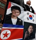 South Korean protesters hold a banner showing the pictures of South Korean President Park Geun-hye and flag, top and North Korean leader Kim Jong Un and flag, bottom, during a rally to support the President Park Geun-hye's policy about Kaesong industrial park in Seoul, South Korea, Tuesday, Feb. 16, 2016. (AP Photo/Lee Jin-man)