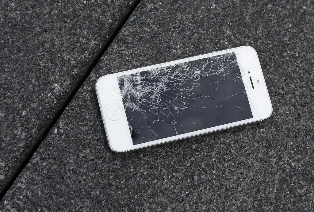 FILE - This Aug. 26, 2015 photo shows an Apple iPhone with a cracked screen after a drop test from the DropBot, a robot used to measure the sustainability of a phone to dropping, at the offices of SquareTrade in San Francisco. Apple for the first time is accepting banged up iPhones as a trade-in from those wanting to upgrade. (AP Photo/Ben Margot)