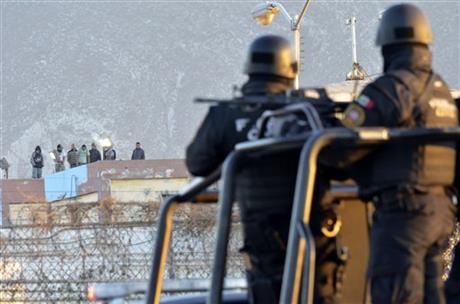 Inmates stand on the rooftop of the Topo Chico prison as police stand guard on the perimeters, after a riot broke out around midnight, in Monterrey, Mexico, Thursday, Feb. 11, 2016. Dozens of inmates were killed and several injured in a brutal fight between two rival factions at the prison in northern Mexico, the state governor said. (AP Photo/Emilio Vazquez)