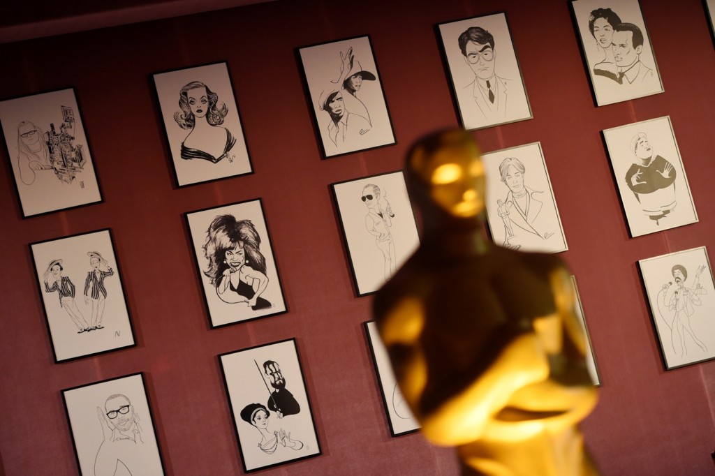 A sample of over 160 caricatures of Hollywood figures created for the Academy Awards Governors Ball are displayed behind an Oscar statue at the 88th Academy Awards Governors Ball Press Preview on Thursday, Feb. 18, 2016, in Los Angeles. The 88th Academy Awards ceremony will be held at the Dolby Theatre in Los Angeles on Sunday, Feb. 28. (Photo by Chris Pizzello/Invision/AP)