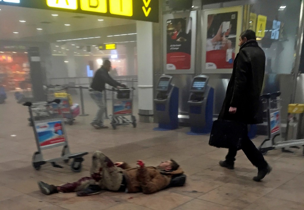In this photo provided by Georgian Public Broadcaster and photographed by Ketevan Kardava, an injured man lies on the floor in Brussels Airport in Brussels, Belgium, after explosions were heard Tuesday, March 22, 2016. A developing situation left a number dead in explosions that ripped through the departure hall at Brussels airport Tuesday, police said. All flights were canceled, arriving planes were being diverted and Belgium's terror alert level was raised to maximum, officials said. (Ketevan Kardava/ Georgian Public Broadcaster via AP)