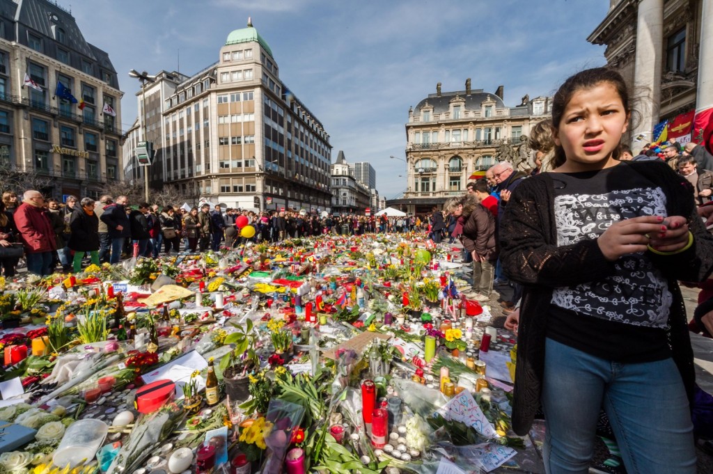 People stop and look at floral tributes at a memorial site at the Place de la Bourse in Brussels, Saturday, March 26, 2016. Brussels airport officials say flights won't resume before Tuesday as they assess the damage caused by twin explosions in the terminal earlier this week. (AP Photo/Geert Vanden Wijngaert)