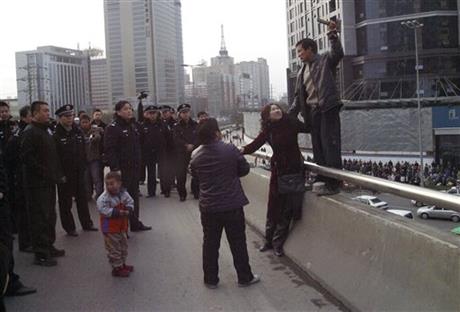 In this Dec. 8, 2006 photo, Pu Zhengxing, right, a carpenter trying to get back his unpaid wage of 3,000 yuan, takes hostage the wife of his foreman in Xi'an of China's Shaanxi province. Policemen eventually saved the hostage and arrested Pu. Wage arrears are a major problem for Chinese laborers, especially migrants working on casual terms in the construction industry. (Color China Photo via AP)