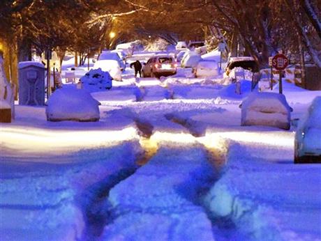 A person works to dig out a vehicle stuck in the middle of Jennings Street in Sioux City, Iowa's, north side early Thursday morning, March 24, 2016. A spring snow storm dropped about 14-inches of snow in Sioux City according to the National Weather Service. (Tim Hynds/Sioux City Journal via AP)