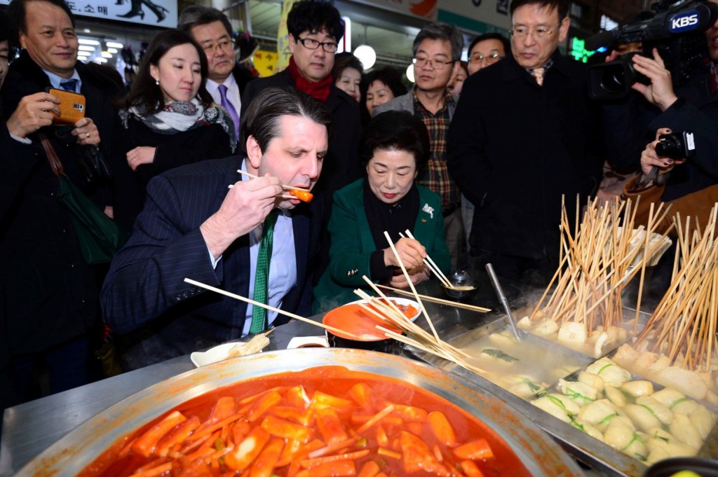FILE - This file photo dated Feb 27, 2015 shows   U.S. Ambassador to South Korea Mark Lippert trying popular Korean street food tteokbokki at a street market in Busan. (Newsis)