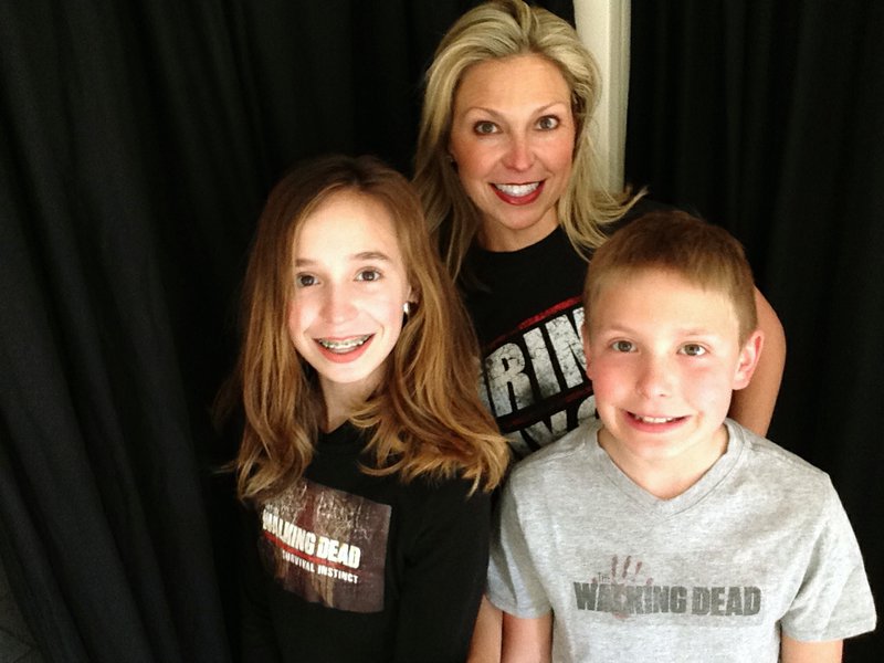 This March 29, 2016 photo released by Ericka Calcagno, center, shows her with her daughter Gina Binder, 12, left, and son Jean-Luc Binder, 9, wearing T-shirts from, "The Walking Dead," at their home in Farmington Hills, Mich. Calcagno says her husband first introduced her to the series and her kids were intrigued by their conversations about it. And now they all watch the popular zombie show as a family. (Ericka Calcagno via AP)