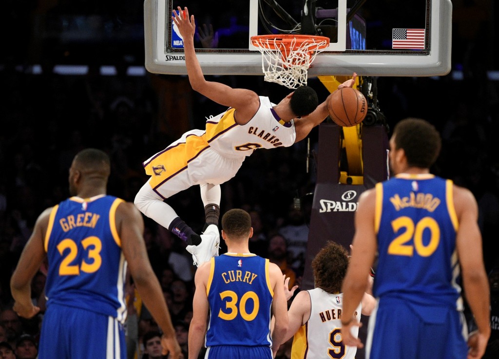 Los Angeles Lakers guard Jordan Clarkson, top, falls from the rim after a dunk during the second half of an NBA basketball game against the Golden State Warriors in Los Angeles, Sunday, March 6, 2016. The Los Angeles Lakers won 112-95. (AP Photo/Kelvin Kuo)