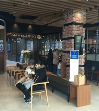 Two customers talk to each other while waiting to handle their financial transactions in a Woori Bank outlet which opened a 'cafe in branch' in Yongsan, central Seoul, on March 28, 2016 in this photo provided by the bank. (Yonhap)