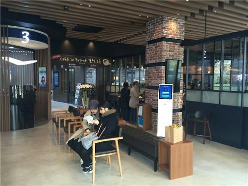 Two customers talk to each other while waiting to handle their financial transactions in a Woori Bank outlet which opened a 'cafe in branch' in Yongsan, central Seoul, on March 28, 2016 in this photo provided by the bank. (Yonhap)