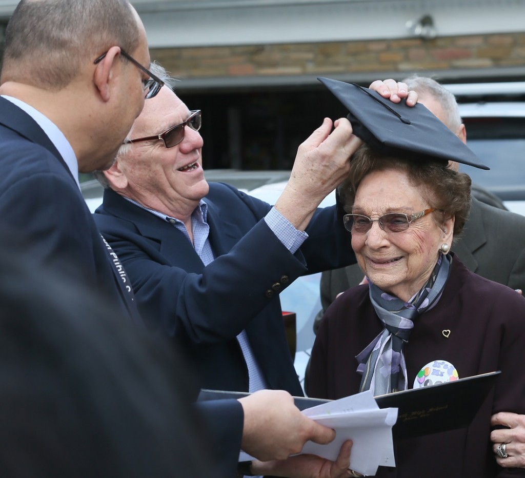 Donald Huston, center, puts a graduation cap on his mother, Dorothy L. Liggett as Akron Schools Superintendent David James, left, presents her belated North High School diploma on Wednesday, March 9, 2016, in Fairlawn, Ohio. Liggett was a few weeks from graduation from Akron's North High School in 1942 when officials discovered she was married. Liggett and her late husband, John Huston, ran away to Kentucky to get married after her husband was called into the U.S. Army Air Corps during World War II. (Michael Chritton/Akron Beacon Journal via AP)   