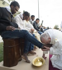 Pope Francis kisses the foot of a man during the foot-washing ritual at the Castelnuovo di Porto refugees center, some 30km (18, 6 miles) from Rome, Thursday, March 24, 2016. The pontiff washed and kissed the feet of Muslim, Orthodox, Hindu and Catholic refugees Thursday, declaring them children of the same God, in a gesture of welcome and brotherhood at a time when anti-Muslim and anti-immigrant sentiment has spiked following the Brussels attacks. (L'Osservatore Romano/Pool Photo via AP)