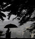 A man and woman walk along a path under trees at Alamo Square Park in San Francisco, Thursday, March 3, 2016. Light rain has started in the San Francisco Bay Area as the region braces for a series of storms expected this weekend and into next week. (AP Photo/Jeff Chiu)