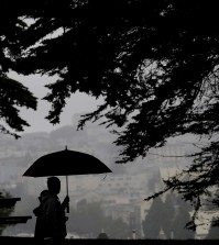 A man and woman walk along a path under trees at Alamo Square Park in San Francisco, Thursday, March 3, 2016. Light rain has started in the San Francisco Bay Area as the region braces for a series of storms expected this weekend and into next week. (AP Photo/Jeff Chiu)