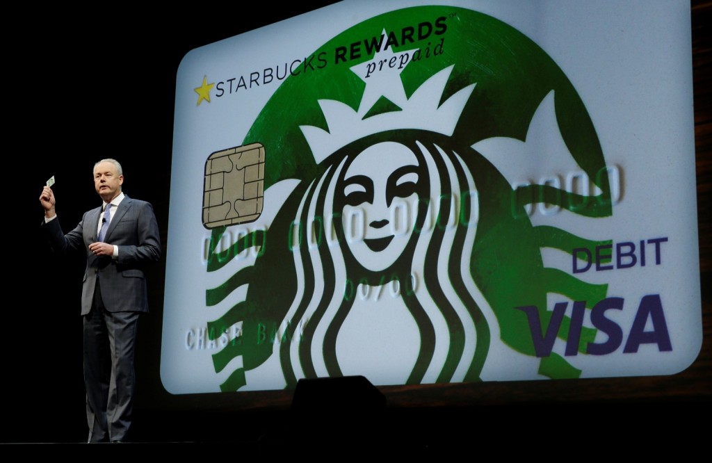 Kevin Johnson, president and chief operating officer of Starbucks Corp., holds up one of the coffee company's new prepaid Visa debit cards, Wednesday, March 23, 2016, at the coffee company's annual shareholders meeting in Seattle. The card can be pre-loaded with money and used for purchases anywhere Visa is accepted, earning the user Starbucks rewards, which can be used to buy Starbucks products. (AP Photo/Ted S. Warren)