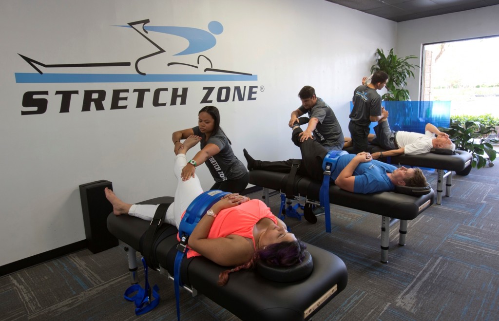 In this March 17, 2016 photo, stretching techniques are demonstrated in at Stretch Zone in Boca Raton, Fla. Some chiropractors and trainers say they’re treating more injured clients as the high intensity interval training and hybrid-workout movement has exploded. Most CrossFit and similar high intensity workouts are not meant for average gym-goers, said Jorden Gold, who founded Stretch Zone. During the 30-minute sessions, therapists use bolsters and belts to stretch clients on a table from angles that are nearly impossible to stretch on one’s own. (AP Photo/Wilfredo Lee)