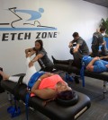 In this March 17, 2016 photo, stretching techniques are demonstrated in at Stretch Zone in Boca Raton, Fla. Some chiropractors and trainers say they’re treating more injured clients as the high intensity interval training and hybrid-workout movement has exploded. Most CrossFit and similar high intensity workouts are not meant for average gym-goers, said Jorden Gold, who founded Stretch Zone. During the 30-minute sessions, therapists use bolsters and belts to stretch clients on a table from angles that are nearly impossible to stretch on one’s own. (AP Photo/Wilfredo Lee)