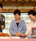 President Park Geun-hye (C) learns how to make Korean traditional dessert cakes with Song Joong-ki (L), the actor of the hit drama "Descendants of the Sun," and Yoon Suk-ja, the chief of the Korean Food Foundation, during the opening ceremony of the "K-Style Hub" in Seoul on April 11, 2016. (Yonhap)