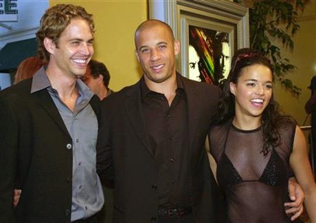 FILE - In this June 18, 2001 file photo, from left, Paul Walker, Vin Diesel, and Michelle Rodriguez, arrive at the world premiere of "The Fast and the Furious," in the Westwood section of Los Angeles. Universal Pictures announced Wednesday, May 25, 2016 that it will re-release the film in a limited run on June 22, to commemorate its 15th anniversary. (AP Photo/Chris Weeks, File)