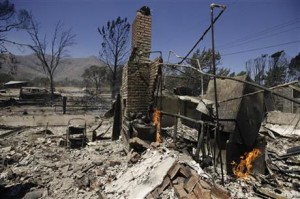 A home smolders after it was destroyed by a wildfire Friday, June 24, 2016, near Lake Isabella, Calif. The wildfire that roared across dry brush and trees in the mountains of central California gave residents little time to flee as flames burned homes to the ground, propane tanks exploded and smoke obscured the path to safety.