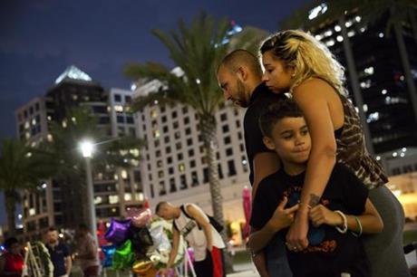 Jennifer Johnson, right, leans on her boyfriend Jeansem Sambolin while standing with her son Tyrone Clarke, 8, as they visit a makeshift memorial for the victims of the mass shooting at the Pulse Orlando nightclub Tuesday, June 14, 2016, in Orlando, Fla. Franky Jimmy Dejesus Velazquez was one of those killed and had worked with Johnson.