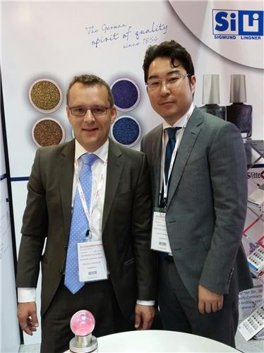 This photo taken on July 7, 2016, Erwin Pschierer, head of product management at Sigmund Lindner GmbH, poses for a photo with his Korean colleague in the company's booth during the 'in-cosmetics Korea' exhibition held in Seoul on July 6-7. (Yonhap)