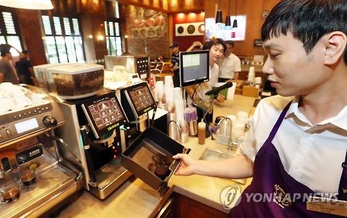 An employee collects coffee dregs at a coffee shop in Seoul's Jongno Ward on Aug. 1, 2016, as the shop takes part in a pilot project, implemented by the Seoul metropolitan government, to reuse them as a compost for mushroom growing or fodder.