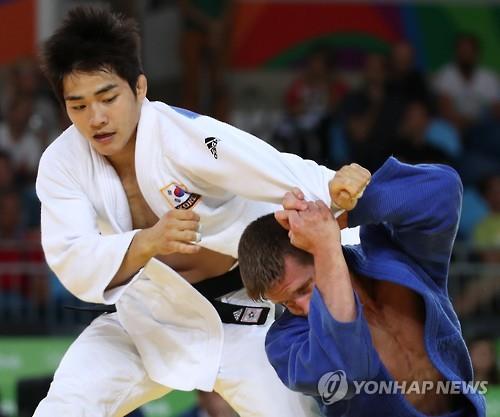 South Korea's An Chang-rim (L) battles Dirk van Tichelt of Belgium in the round of 16 contest in the men's -73kg judo at the Rio de Janeiro Olympics on Aug. 8, 2016.